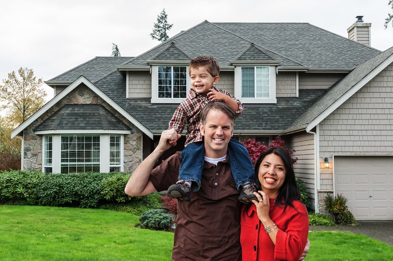 couple and son stand outside beautiful home