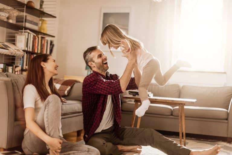 happy couple playing with young daughter in living room